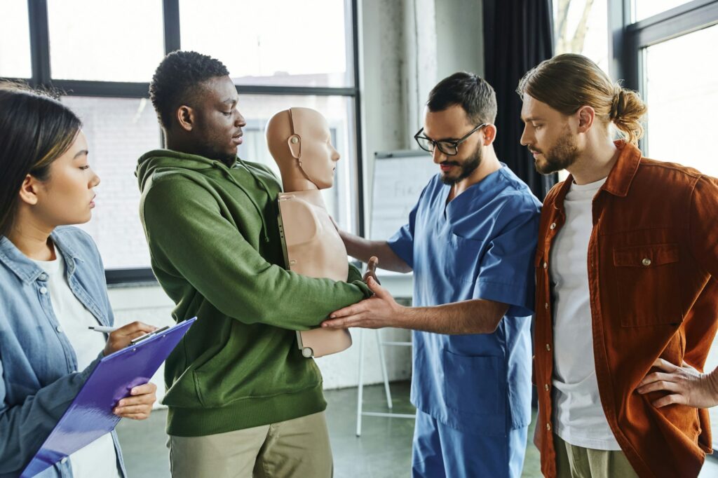 medical instructor assisting african american man practicing life-saving techniques in case of